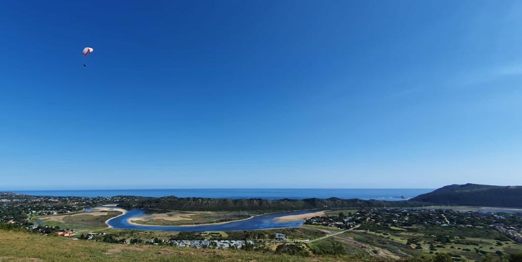 A single paraglider flying over Swartvlei Lagoon in Sedgefield